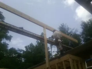 Carpenter setting a ridge beam over a new addition frame — Ice Dam Removal by Roofing Brothers in Ona