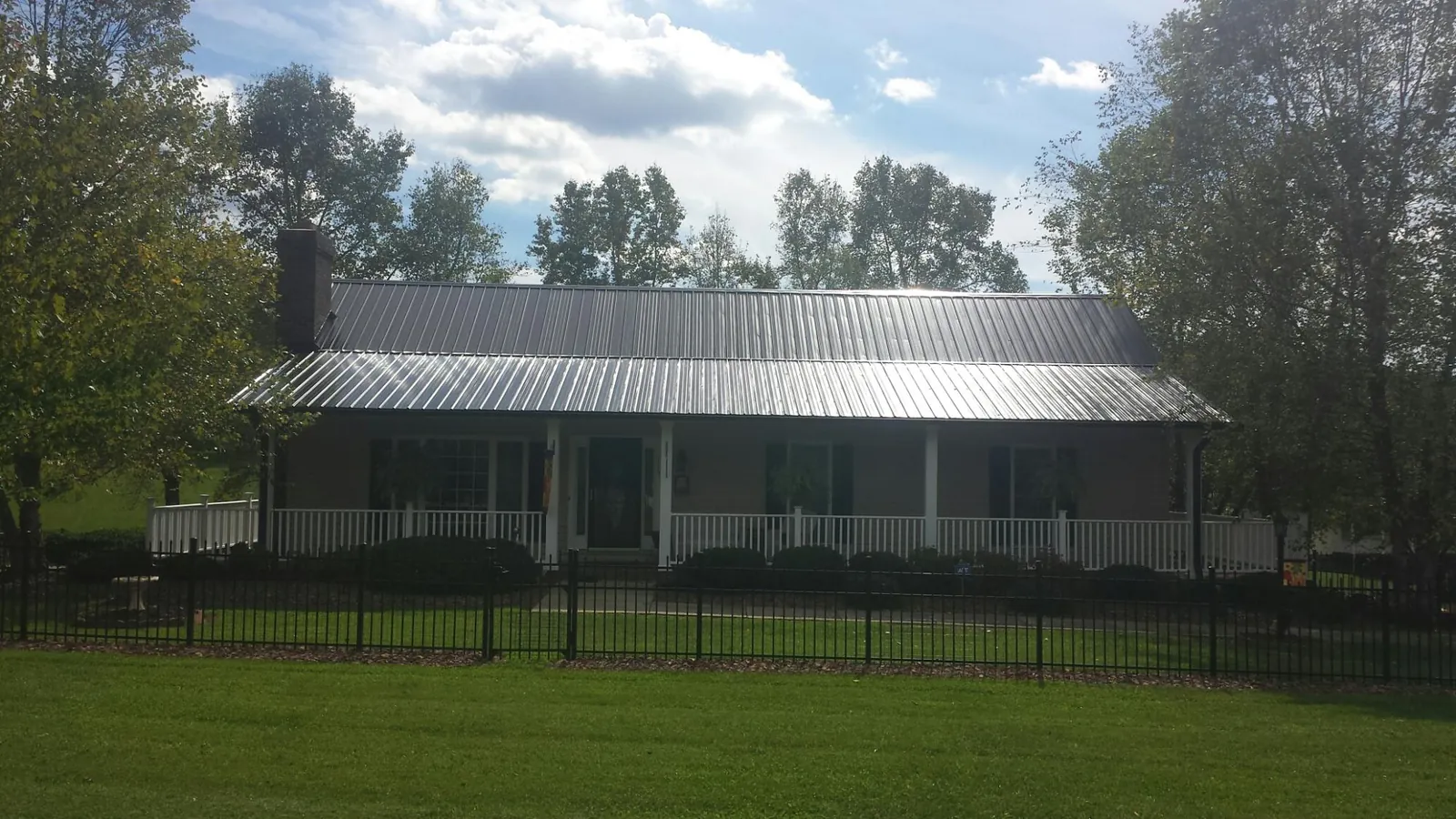 Gray metal roof on a brick ranch with a full width front porch — Gutter Guard Installation work by our crew in Ona