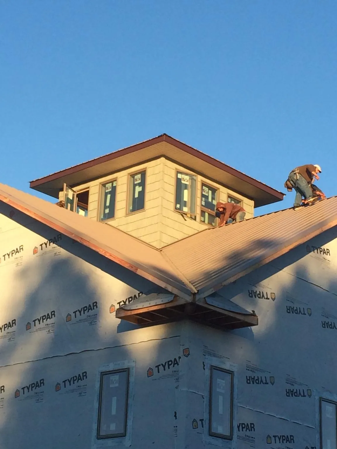 Roofers working around a rooftop cupola on a new metal roof at sunset — Roof Waterproofing in Ona by Roofing Brothers